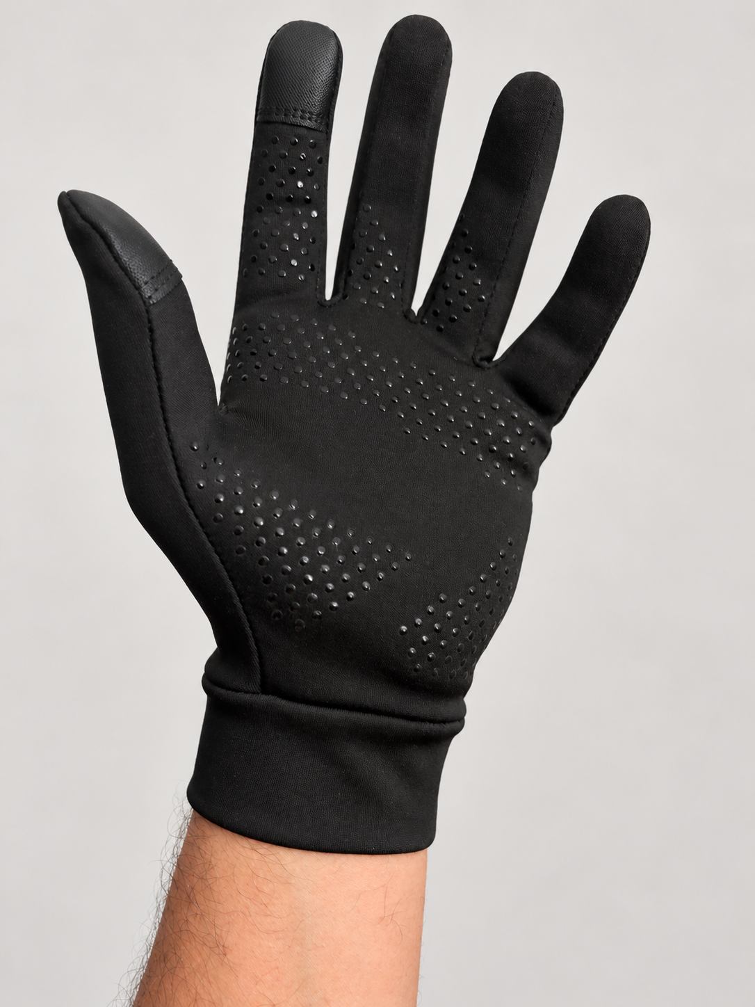 Palm of a black NW glove worn on a hand, showing dotted grip texture and thumb and index fingertip panels